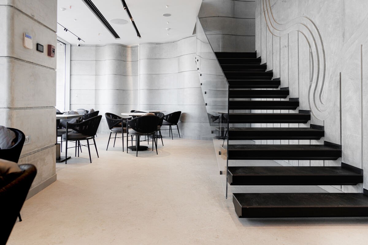 Mocha's floating black staircase against the carved concrete wall